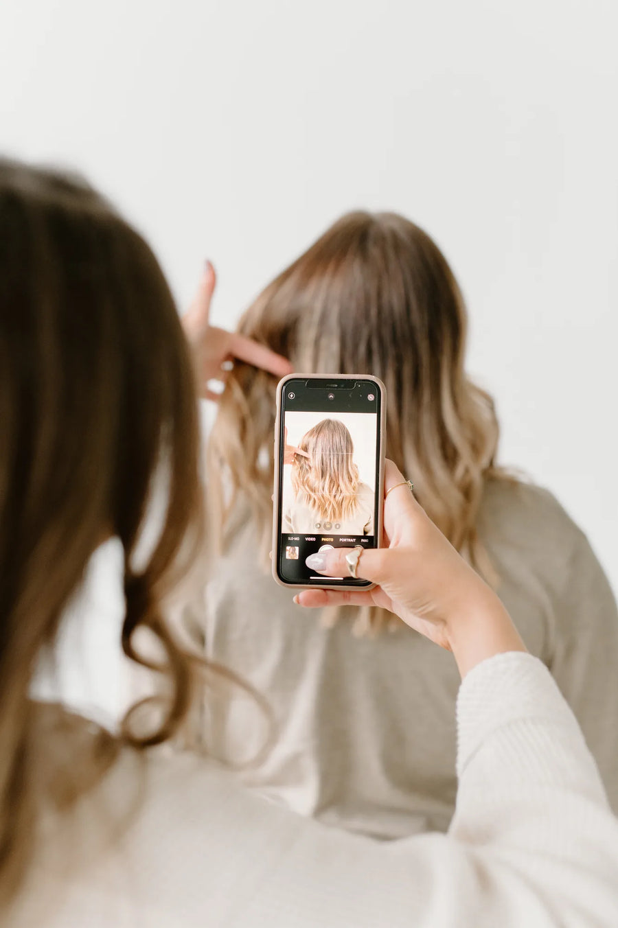 Moda Salon stylist photographing blonde hair on a phone