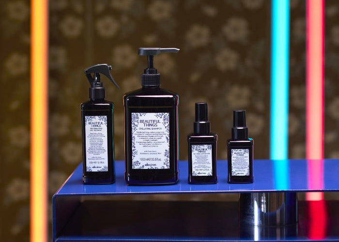 Four black bottles with labels on a blue surface against a patterned background