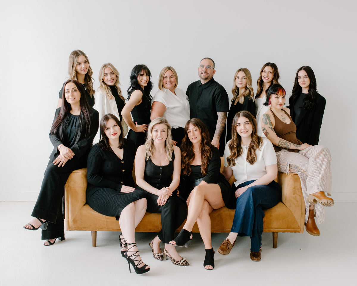 Group of people posing together on a couch against a white background