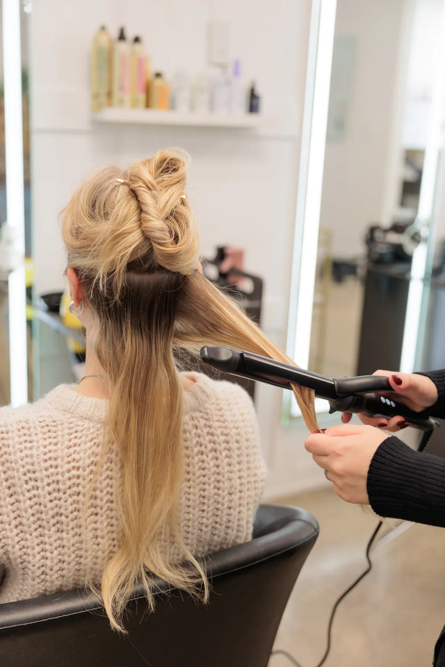 Stylist curling dense blonde hair in the salon
